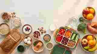 Flat lay of healthy lunchbox ingredients including oats, nuts, yogurt, eggs, salmon, milk and fresh produce